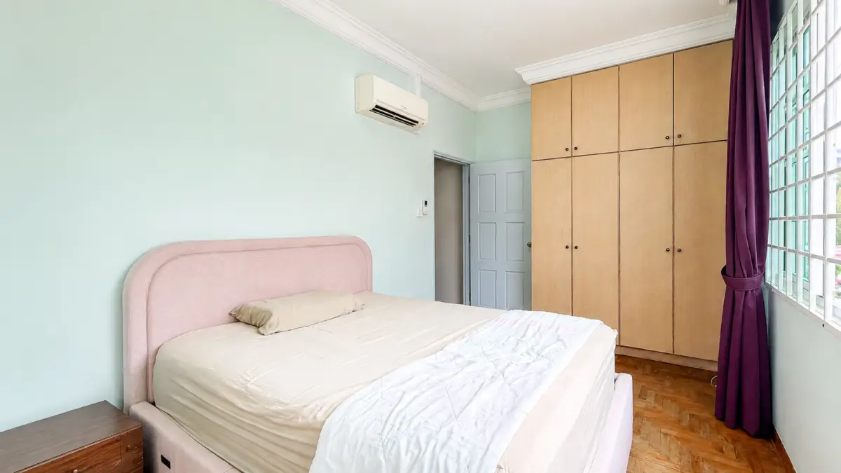 Bedroom with a pink upholstered bed, beige bedding, and a large wooden wardrobe beside a window with purple curtains.