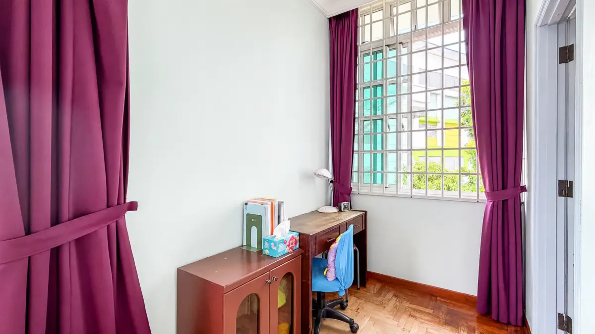 Cozy study area with a wooden desk, blue swivel chair, and maroon curtains by a large grid window.
