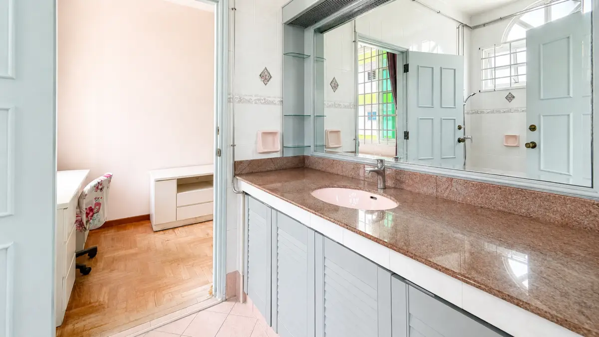 Bathroom with a pink sink set in a brown granite countertop, pale blue cabinets, and a large mirror above.