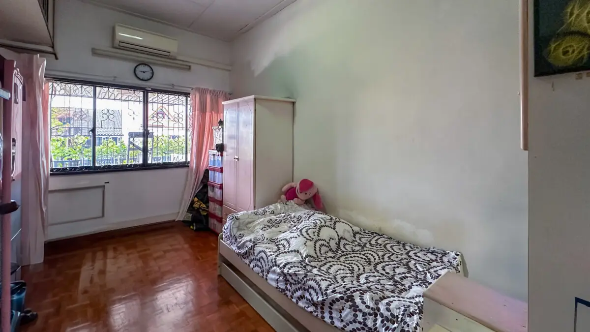 Small bedroom with a single bed along the wall, patterned blanket, and a pink wardrobe nearby.