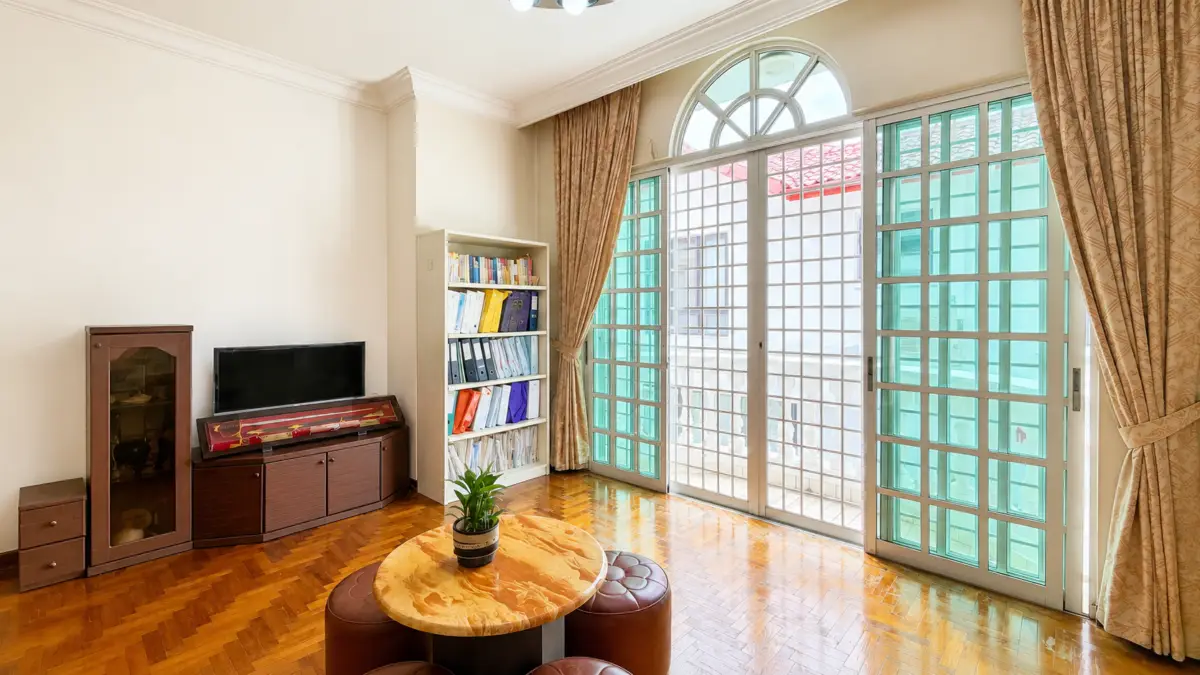 Bright living room with an arched window and glass doors, round marble coffee table, plant, and brown ottomans.