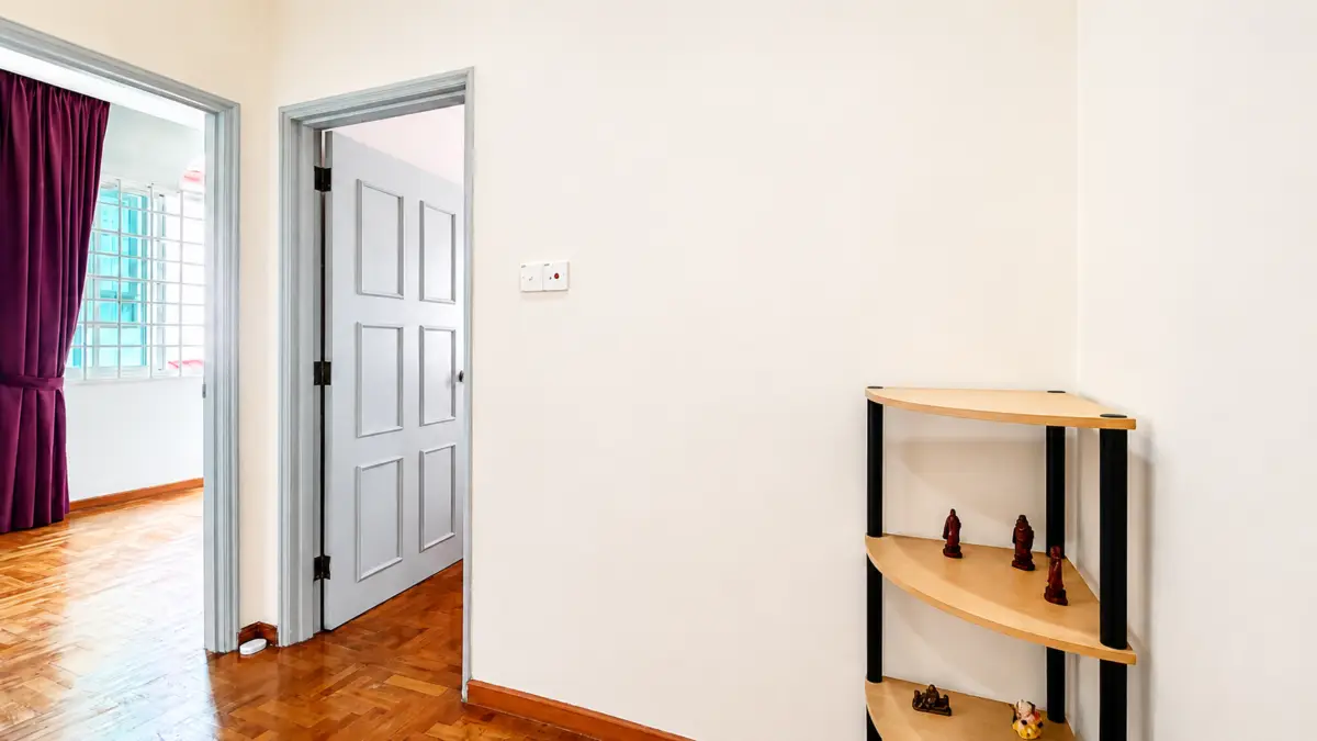 Bright hallway with a gray paneled door open to a room with purple curtains and a window; a curved wooden shelf holds chess pieces on the right.