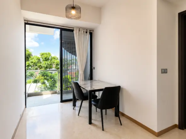 Compact dining nook by a sliding glass door to a sunlit balcony, marble-top table with two black chairs nearby.