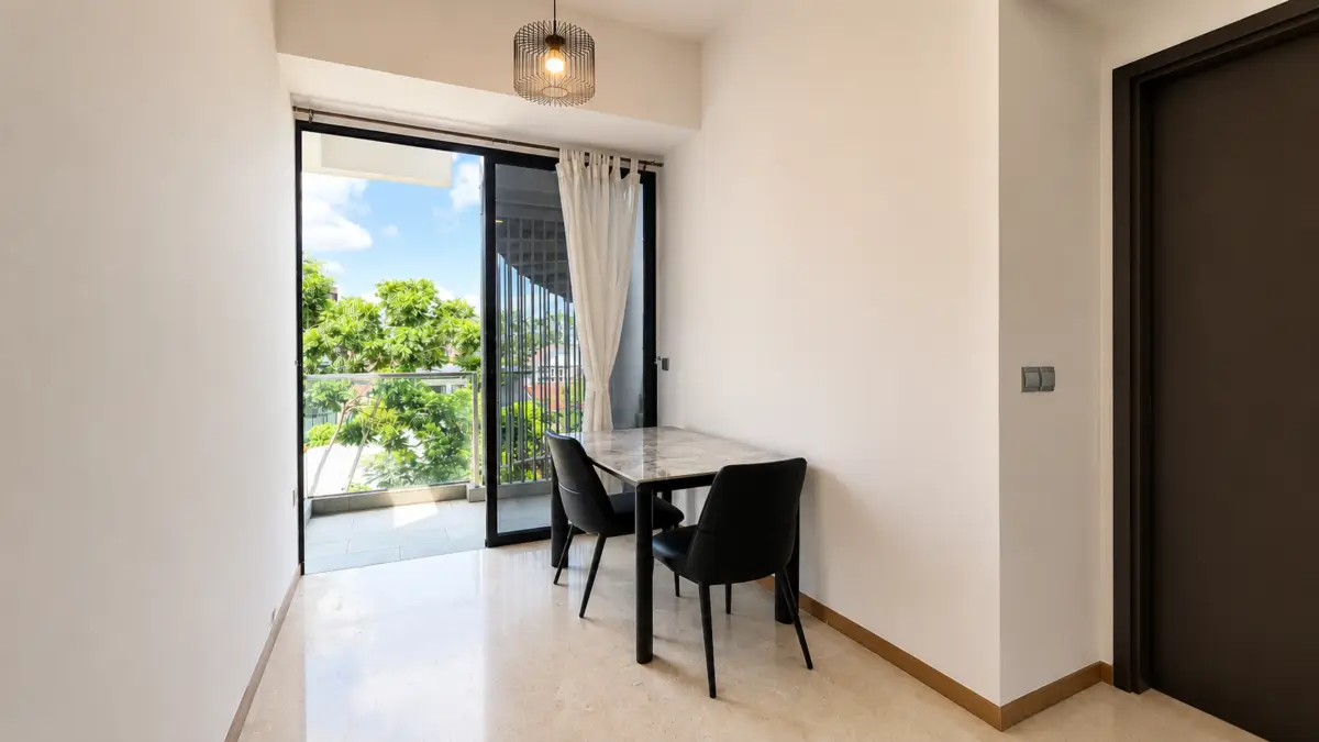 Compact dining nook by a sliding glass door to a sunlit balcony, marble-top table with two black chairs nearby.