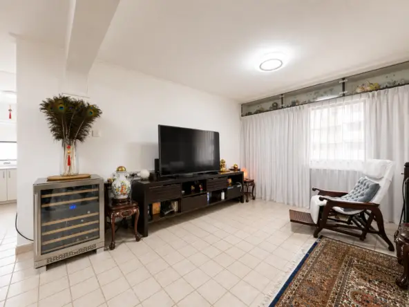 Living room with a large flat-screen TV on a dark wooden console, decorative items, and a wine cooler to the left.