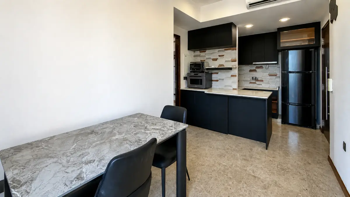 Modern kitchen with black cabinets, stainless fridge, and hexagonal tile backsplash; marble dining table in foreground.