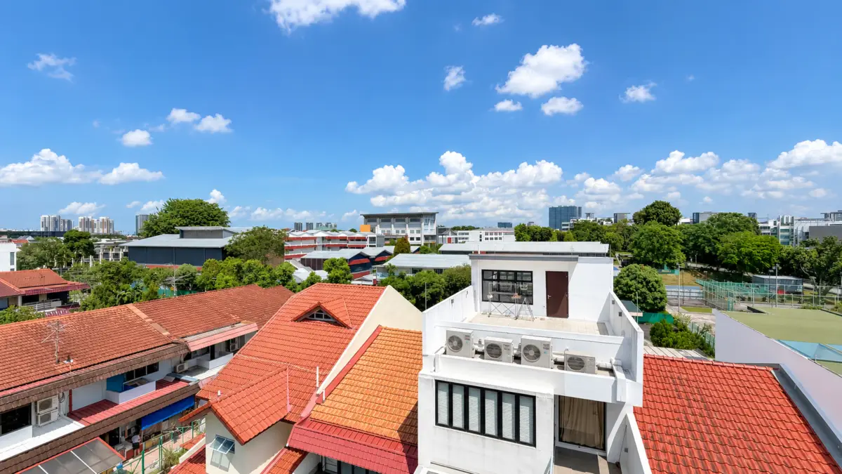 Wide view over a sunny urban neighborhood with red-tiled roofs and white buildings under a blue sky and scattered clouds.”] ,