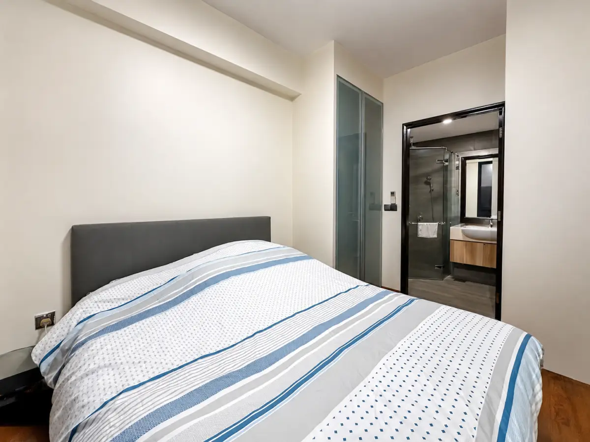 Bedroom with a gray headboard, striped blue and white bedding, and access to a glass-walled bathroom through an open door.