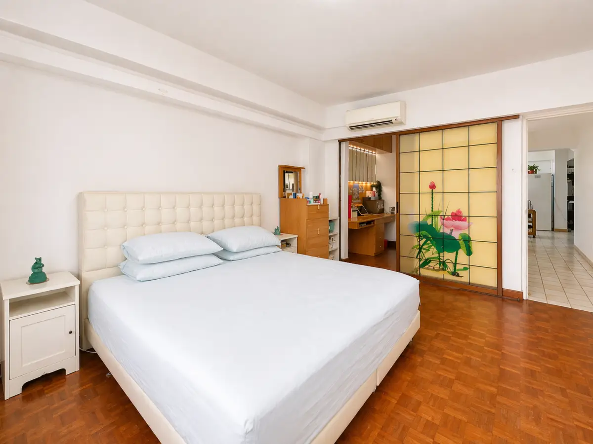 Bright bedroom with a large upholstered bed, light blue bedding, white nightstand, and a wooden floor.