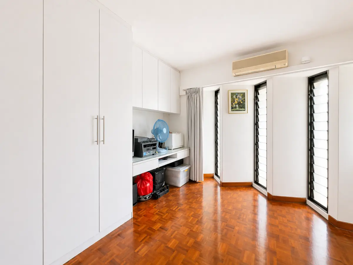 Bright home office with white built-in cabinets, desk, printer, and blue fan on a wood floor.