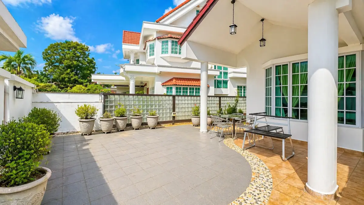 Sunny residential courtyard with white building, columned patio, and outdoor seating under a blue sky.