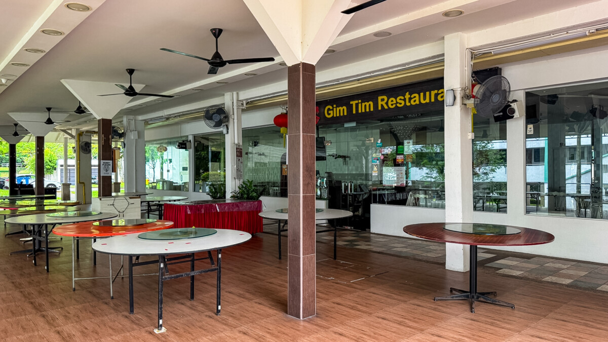 Open-air dining area with round tables and ceiling fans outside Gim Tim Restaurant.