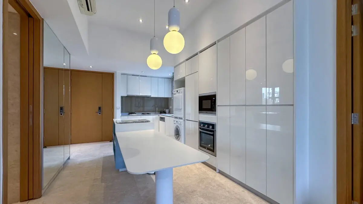 Bright modern kitchen with glossy white cabinets, an island, built-in oven and microwave, and pendant lights above
