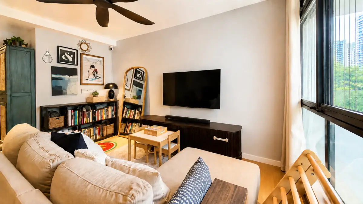 Cozy living room with a beige sectional, wall-mounted TV, and a dark media console beside a large windowed wall.
