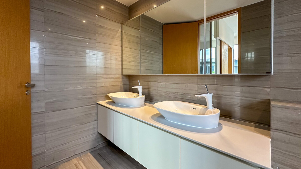 Modern bathroom with a long white vanity, two oval vessel sinks and tall faucets, gray tiled walls, and a large mirrored cabinet above.