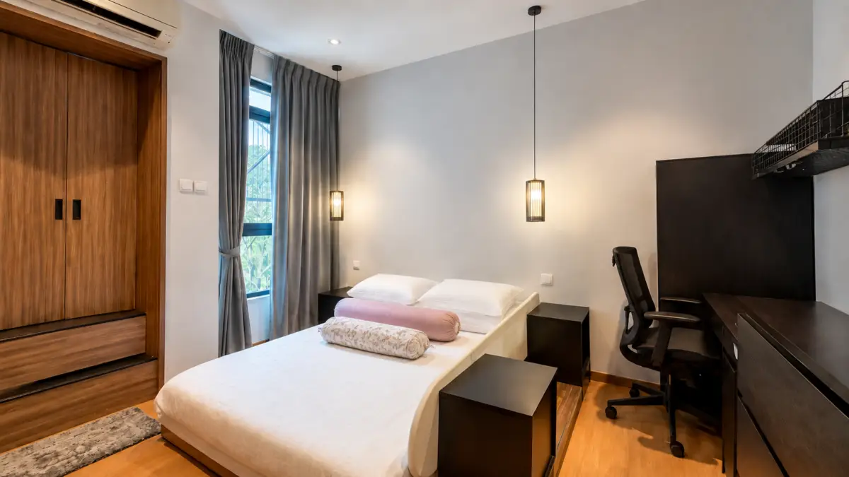 Modern bedroom with a white bed flanked by black nightstands, a black desk and chair, and a wooden wardrobe on the left; window with gray curtains behind.