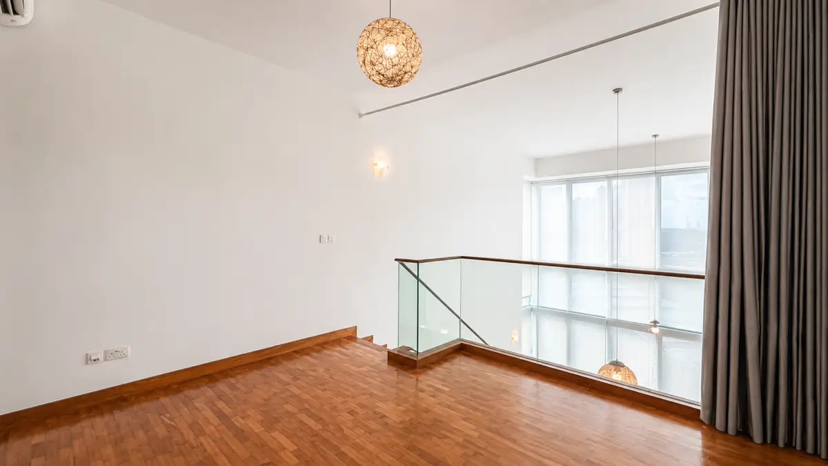 Empty loft landing with wood floor, glass railing, large windows, and woven pendant lights.