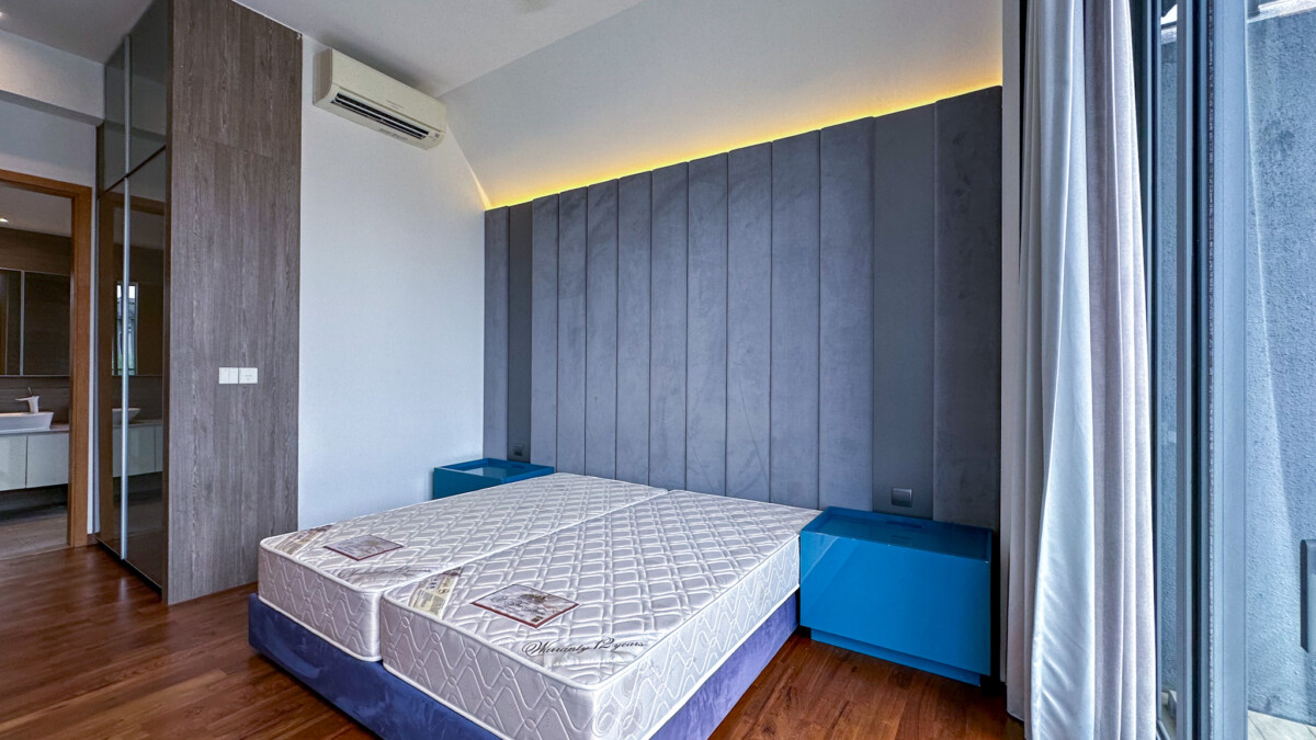 Contemporary bedroom with two adjacent mattresses on a shared base, a tall padded gray headboard, blue nightstands, and warm lighting along the headboard wall.