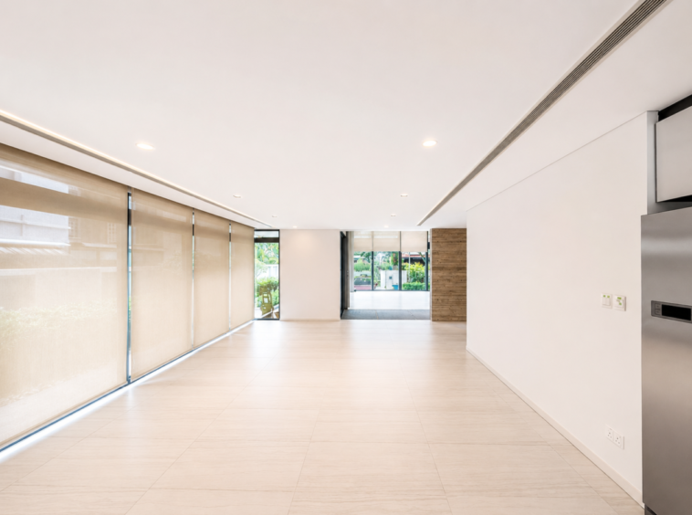Interior modern lobby with large beige roller blinds along left wall and glass doors at the far end; bright, minimalist space with light tiled floor and white walls