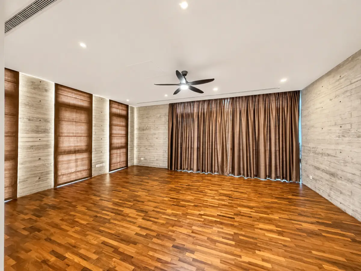 Empty modern living room with dark hardwood floors, light textured walls, and brown floor-to-ceiling curtains under a white ceiling fan with recessed lighting.