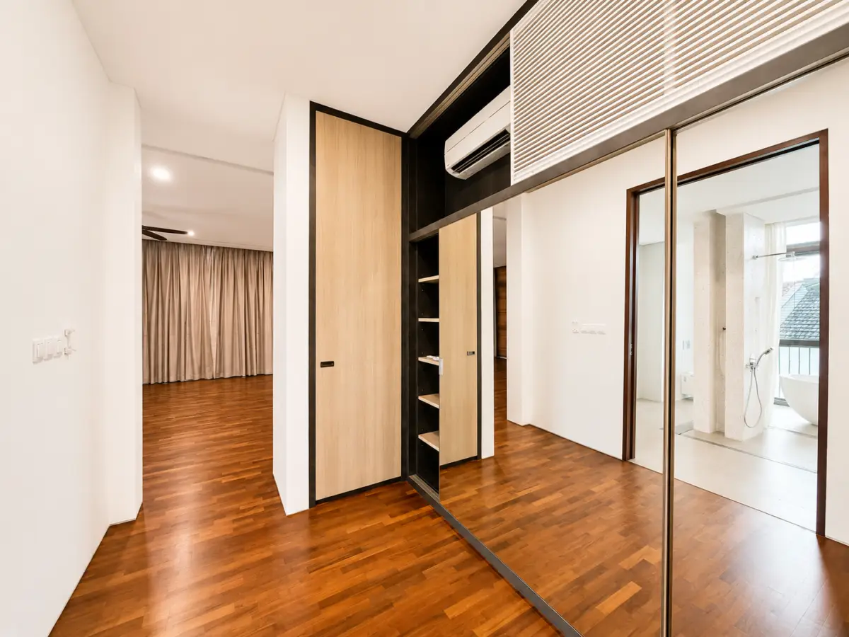 Modern hallway with wooden floors, built-in wardrobe with shelves and mirrored sliding doors, leading to a bathroom area.
