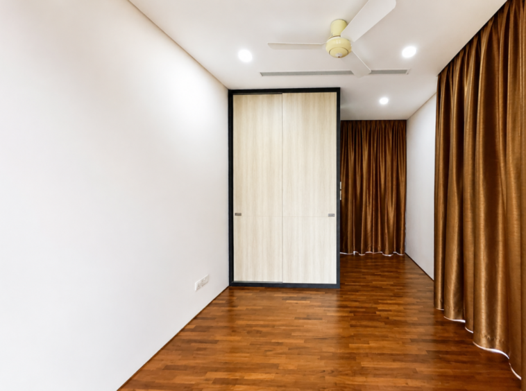 Empty modern room with hardwood floor, white walls, ceiling fan, and a double wooden wardrobe centered in black-framed casing.