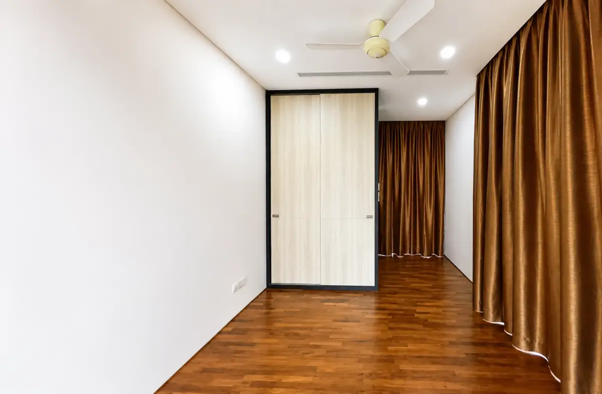 Empty modern room with hardwood floor, white walls, ceiling fan, and a double wooden wardrobe centered in black-framed casing.
