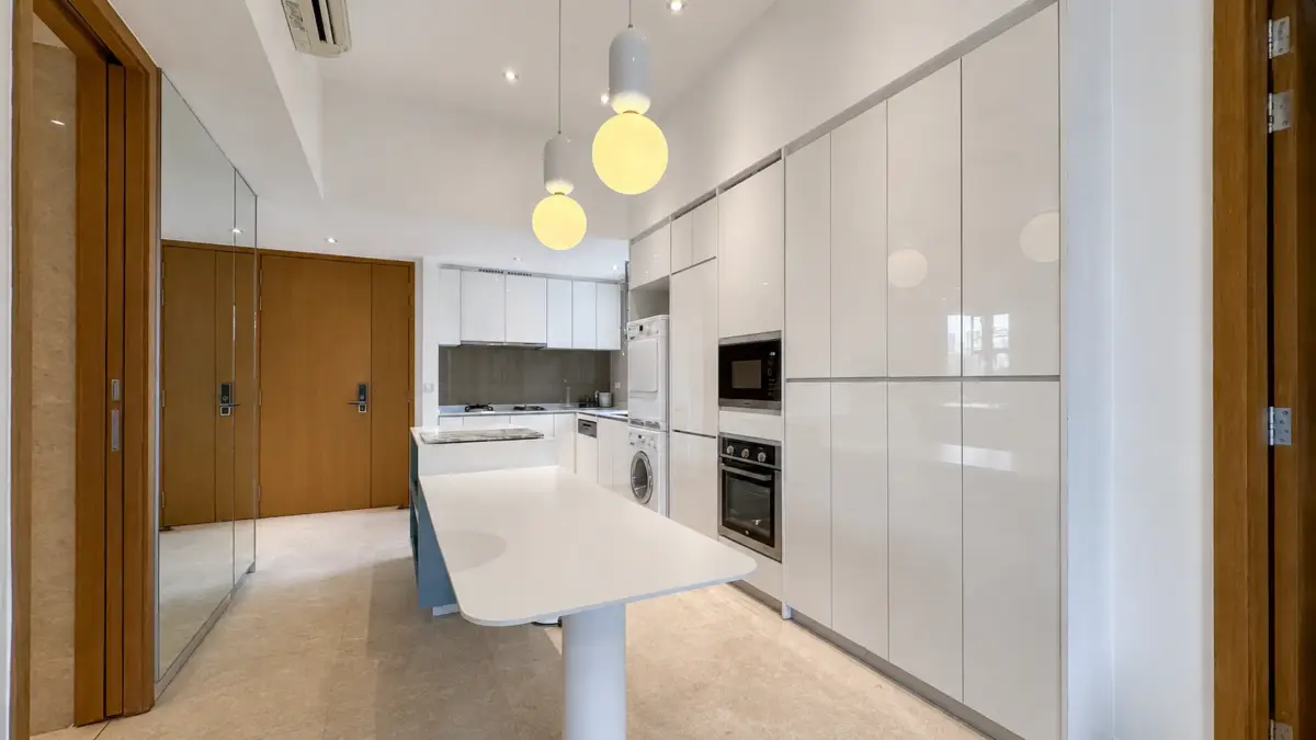 Contemporary white kitchen with tall glossy cabinets and a central white island with a curved edge.
