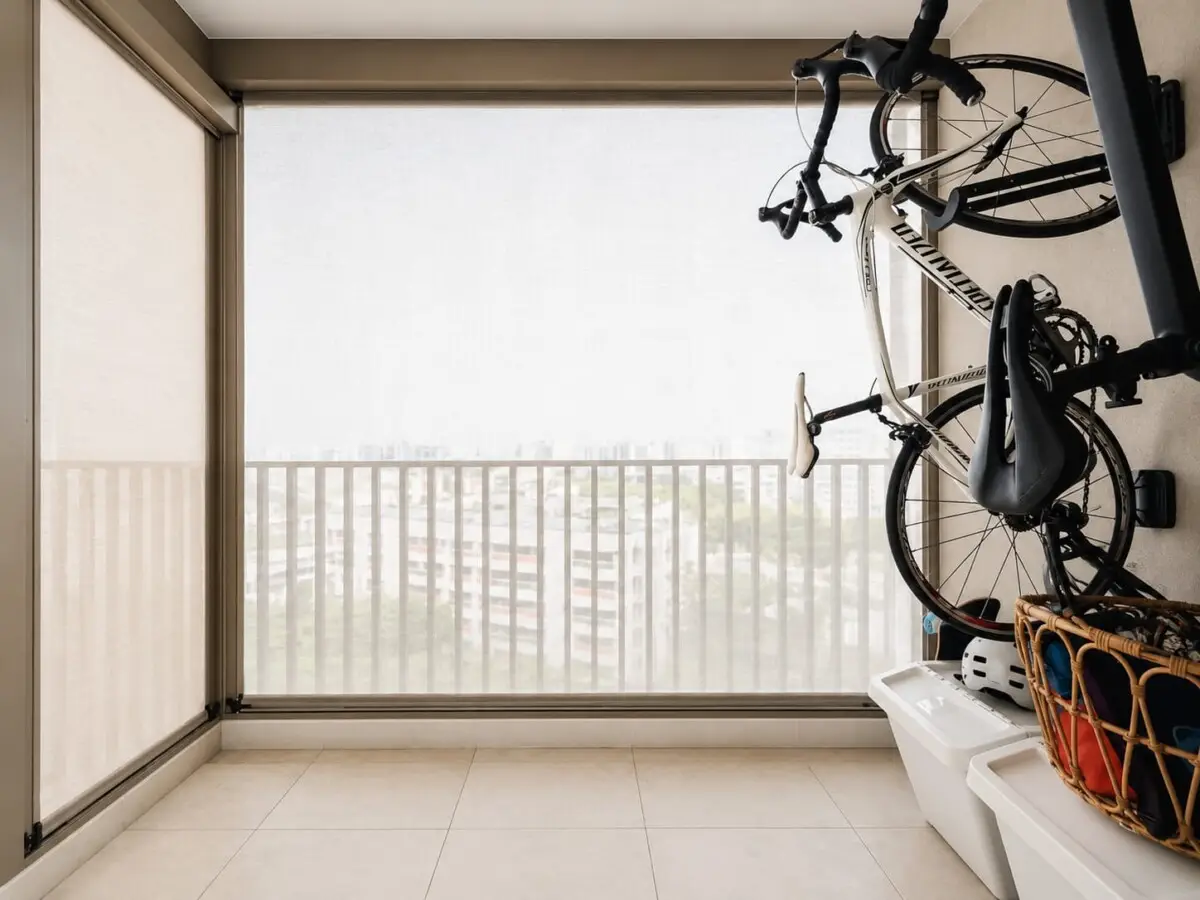 Bicycle storage on a small balcony with two bikes mounted, a helmet, a wicker basket, and white storage bins against a railing view outside