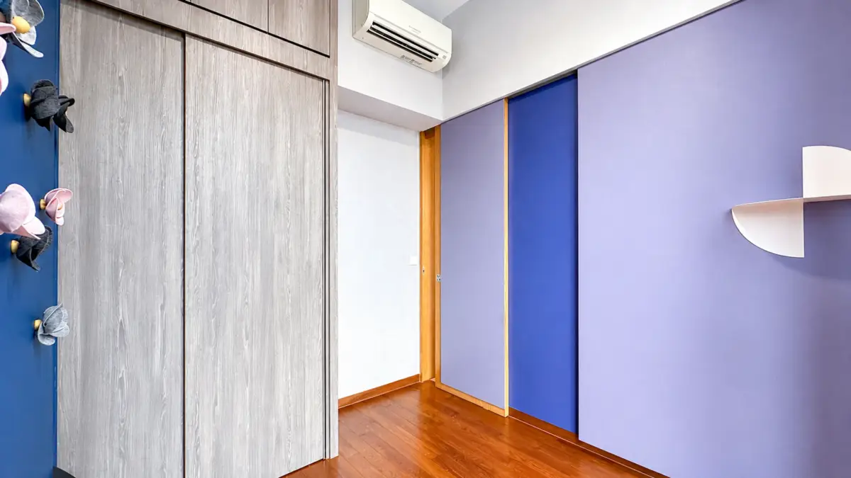 Modern interior hallway with purple walls and blue panels, wooden floor, and gray wood closet doors above.