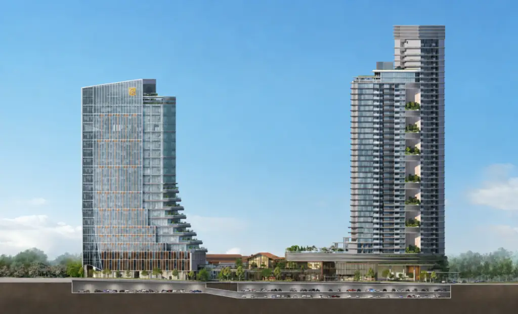 Two modern glass towers connected by a low-rise podium, with terraces and greenery under a clear blue sky.