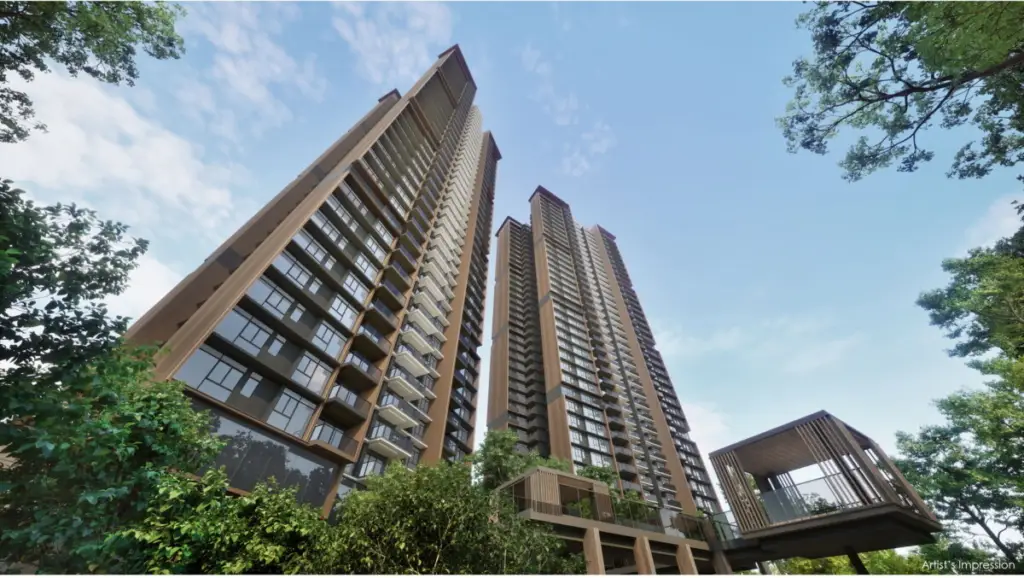 Two tall brown residential towers with glass balconies rise into a blue sky, framed by green trees in the foreground.